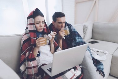 Çift battaniyelere sarılmış kanepede oturuyor. Erkek ve kadın hasta. Bir şey üstünde laptop arıyoruz