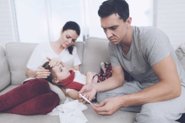 Küçük kız üşütmüş. Anne ve babasıyla ona tedavisi. Kız annesinin kucağında yatıyor