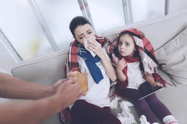 The man brought his wife and daughter hot hot tea. Woman hugging girl and blowing her nose — Stock Photo, Image