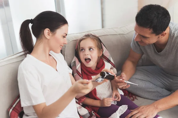 Gadis kecil itu terkena flu. Ibu dan ayahnya yang memperlakukannya. Ibu menuangkan sirup gadis ke sendok — Stok Foto