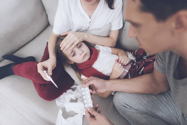 La niña se resfrió. Su madre y su padre la están tratando. La niña yace en el regazo de su madre — Foto de Stock