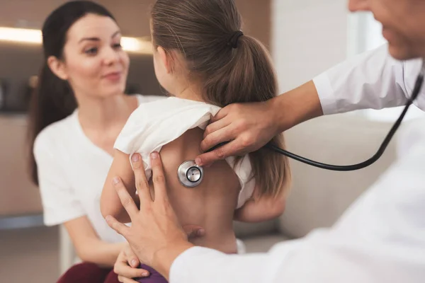 A menina apanhou uma constipação. A mãe dela ligou para o médico em casa. Doutor ouve uma menina com um estetoscópio — Fotografia de Stock