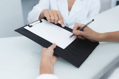 Yakın çekim. Tıbbi bir klinik Sekreteri Hastanın tedaviye başlamadan önce gerekli formları tamamlamak yardımcı olur..