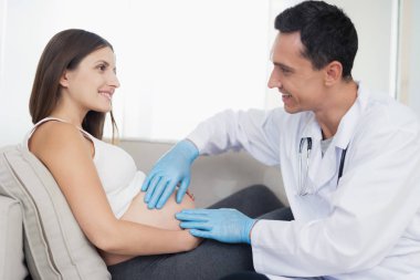 Hamile bir kadın evde ışık kanepede yatıyor. Ona bir doktor geldi, karnı probları