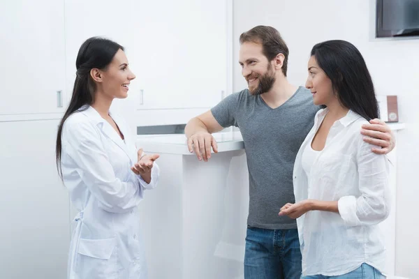 Un hombre y una mujer vinieron a ver a un dentista. La recepcionista rellena el formulario y entrevista a los pacientes . — Foto de Stock