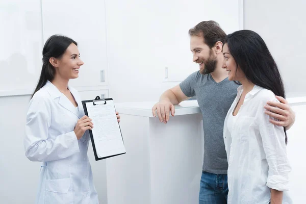 Un hombre y una mujer vinieron a ver a un dentista. La recepcionista rellena el formulario y entrevista a los pacientes . — Foto de Stock