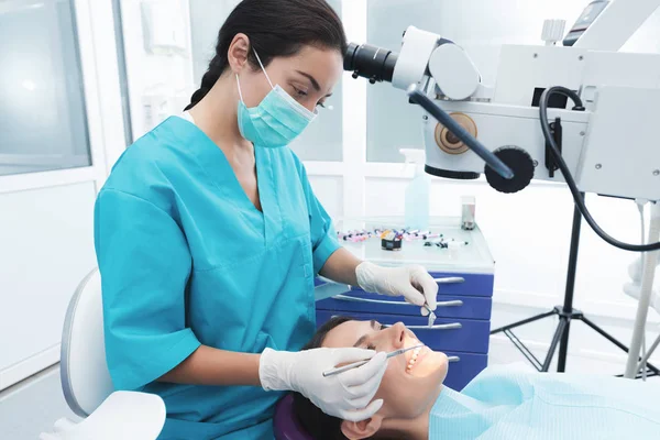 여성 치과 의사는 환자를 치료입니다. 그녀는 치과 자에 앉아. 의사는 특별 한 치과 악기를 사용 하 여. — 스톡 사진
