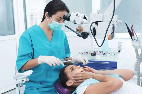 Kvinnliga tandläkare behandlar en patient. Hon sitter på stolen och är rädd. — Stockfoto