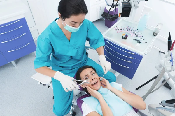 Eine Zahnärztin behandelt eine Patientin. sie sitzt auf dem Zahnarztstuhl und hat Angst. — Stockfoto