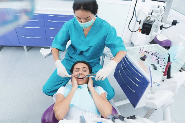 Kobieta dentysty jest traktowanie pacjenta. Ona siada na fotel i się boi. — Zdjęcie stockowe