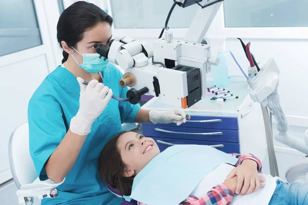 A női fogorvos kezeli a lány. Ő ül a fogorvosi székben, és mosolyog. — Stock Fotó