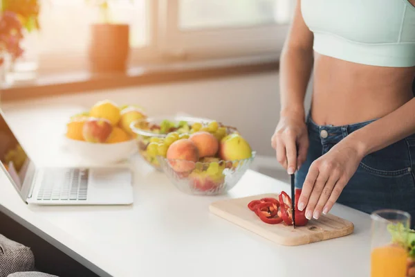 Close up. A young sports girl is standing in the kitchen and is preparing a salad. It has a blue topic. — Stock Photo, Image