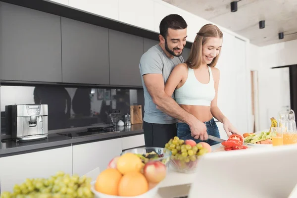 Una pareja está preparando una ensalada para el desayuno. Una chica corta verduras para una ensalada y un hombre la ayuda. . —  Fotos de Stock