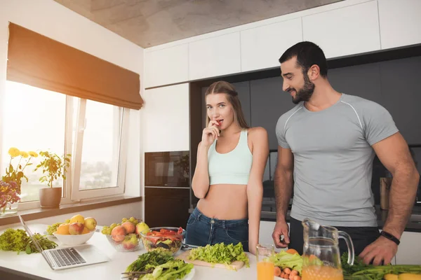 Um casal está preparando uma salada para o café da manhã. Um homem e uma mulher estão posando no processo de cozimento . — Fotografia de Stock