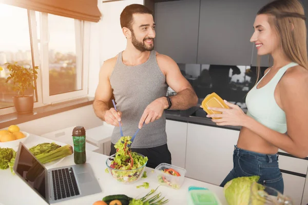 Утром на кухне мужчина и женщина. Мужчина кладет салат на сосуды . — стоковое фото