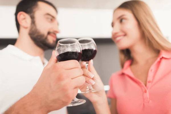 Un hombre y una mujer beben vino en la cocina. Llevan copas de vino en sus manos. . —  Fotos de Stock
