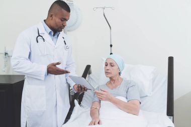 Doktor yanında bir kadınla kanser koğuşunda duruyor.