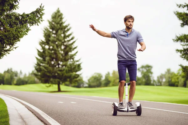 A man is driving through the park on a gyroboard. He enjoys the trip. — Stock Photo, Image