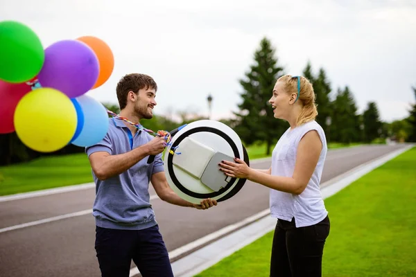 En man ger sin flicka en monokel. Uppblåsbara bollar är kopplade till gadgeten. Hon är glad — Stockfoto