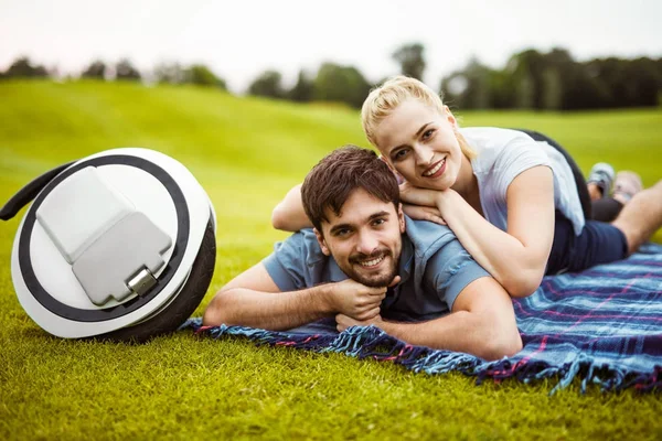 Un jeune couple est allongé sur l'herbe, sur la couverture et se repose après une promenade dans le parc. A proximité est mono-roue — Photo