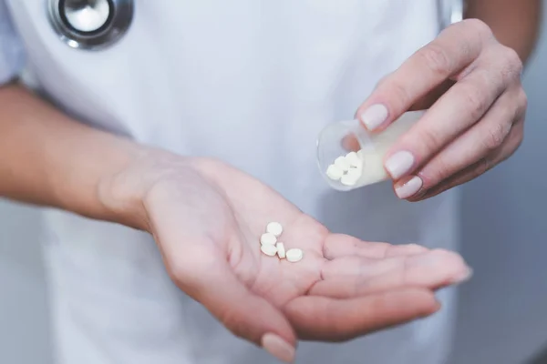 Chiudete. Un'infermiera tiene in mano varie pillole. Li sta mangiando nelle sue mani . — Foto Stock