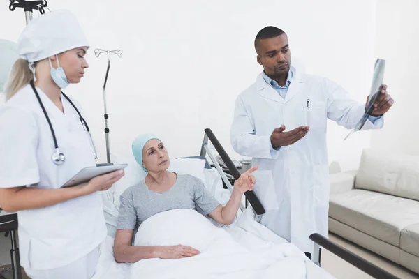 En sjuksköterska är ställning mot patientens bakgrund. Hon håller en tablett i händerna. — Stockfoto