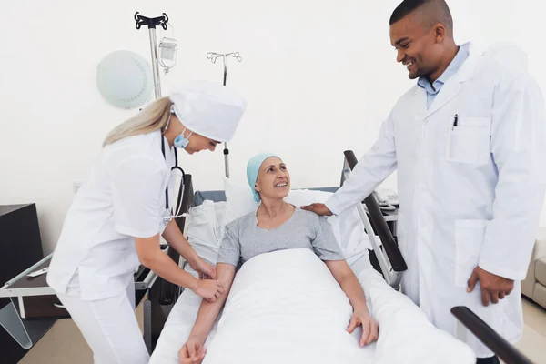 En sjuksköterska sätter en kvinna med en cancer med en pipett. En sjuksköterska har ett stetoskop på hennes hals. — Stockfoto