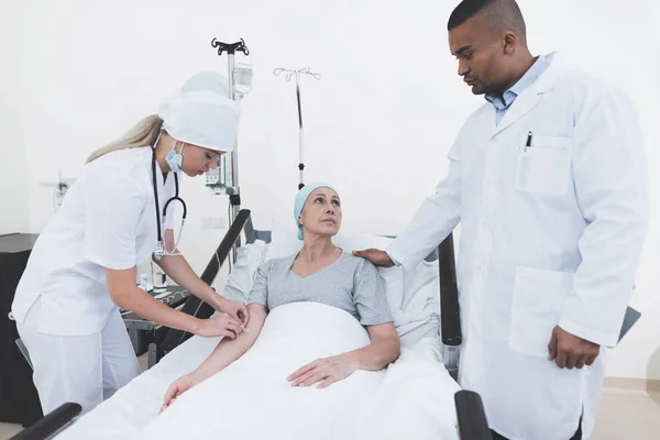 En sjuksköterska sätter en kvinna med en cancer med en pipett. En sjuksköterska har ett stetoskop på hennes hals. — Stockfoto