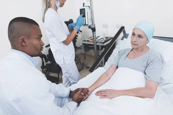 The nurse sets the woman a dropper. A doctor is sitting next to him, who is holding a woman with cancer by the hand. — Stock Photo, Image