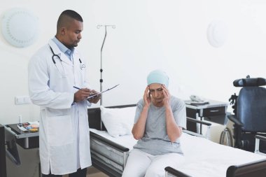 Doktor kadın sorguluyor. Bir kadın kanser tedavisi sonrası rehabilitasyon geçer.