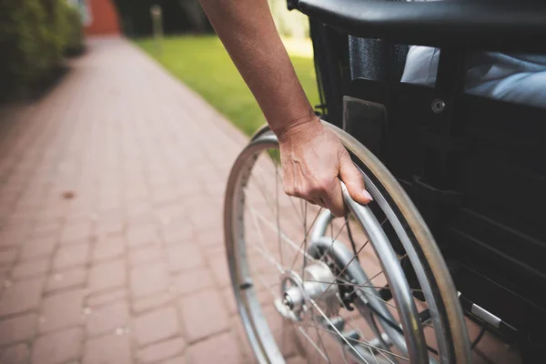 Une femme cancéreuse est assise dans un fauteuil roulant. Elle tient ses mains derrière les roues du fauteuil roulant sur lequel elle est assise . — Photo