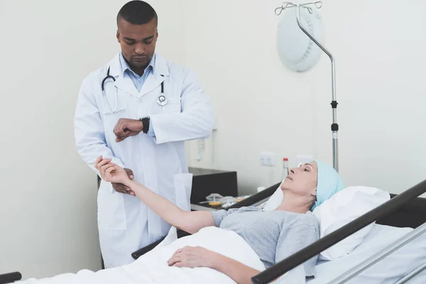 The doctor is measuring the pulse of a woman. A woman undergoes rehabilitation after cancer treatment. — Stock Photo, Image