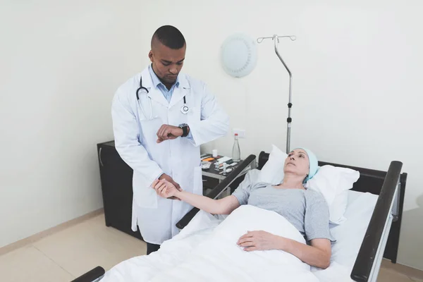 The doctor is measuring the pulse of a woman. A woman undergoes rehabilitation after cancer treatment. — Stock Photo, Image