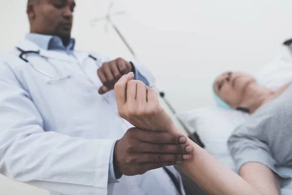 O médico está a medir o pulso de uma mulher. Uma mulher passa por reabilitação após o tratamento do câncer . — Fotografia de Stock