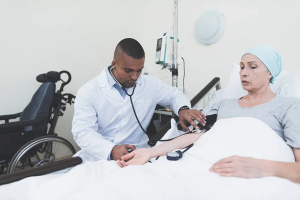 El médico mide la presión sobre la mujer. Una mujer se somete a rehabilitación después del tratamiento del cáncer . —  Fotos de Stock