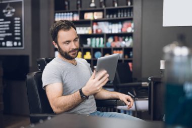 Bir adam bir erkek berber Kuaför'ın sandalyede tablet bakar.
