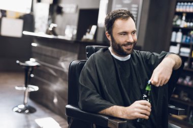 Bir adam alkol modern bir berber Kuaför koltukta içiyor..
