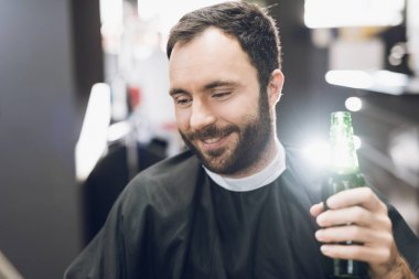 Bir adam alkol modern bir berber Kuaför koltukta içiyor..