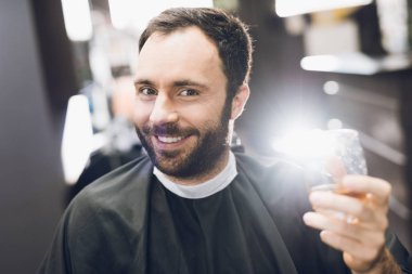 Bir adam alkol modern bir berber Kuaför koltukta içiyor..