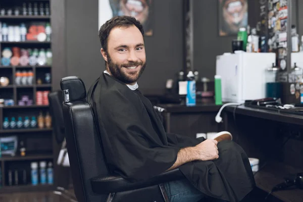 A man sits in a barber's chair in a man's barbershop, where he came to cut his hair. — Stock Photo, Image