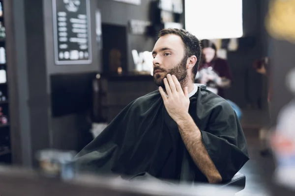 Um homem senta-se na cadeira de um barbeiro na barbearia de um homem, onde veio cortar o cabelo. . — Fotografia de Stock