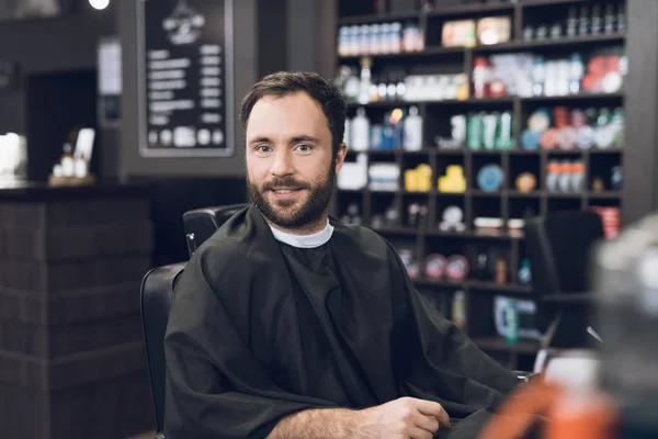 Un uomo si siede su una sedia da barbiere nel barbiere di un uomo, dove è venuto a tagliarsi i capelli . — Foto Stock
