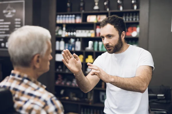 Gubben sitter i barberarens stol i en mans barbershop, där han kom att klippa sitt hår. — Stockfoto