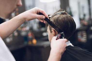 Kuaför güzel şık bir saç modeli için modern bir berber dükkanı çocukta yapar.
