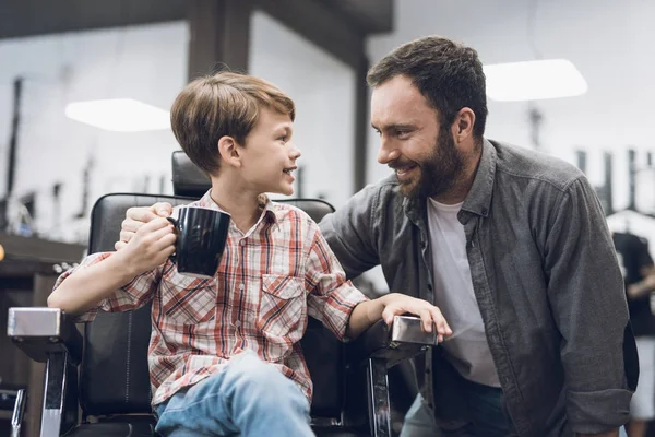 Pojken lyssnar på en vuxen man som sitter i en barbershop Frisör stol. — Stockfoto