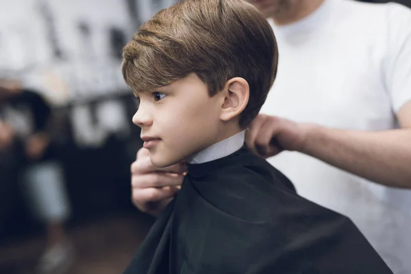 Le coiffeur fait une jolie coiffure à la mode pour le garçon dans un salon de coiffure moderne . — Photo