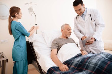 Yaşlı adam yalanlar üzerine bir karyola tıbbi koğuşta ve onun yanında bir doktor duruyor. O tablet yaşlı adam için bir şeyler gösteriyor