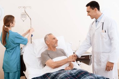 Yaşlı adam yalanlar üzerine bir karyola tıbbi koğuşta ve onun yanında bir doktor duruyor. Doktor yaşlı adamın el sallar.