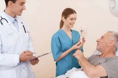 Yaşlı adam yalanlar üzerine bir karyola tıbbi koğuşta ve onun yanında var olan bir doktor ve bir hemşire.
