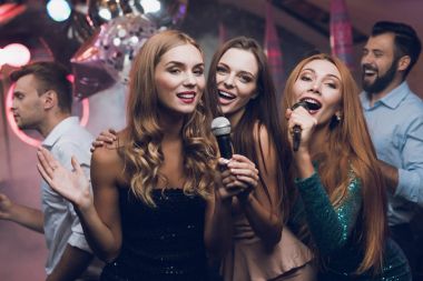 Üç güzel kız bir karaoke kulüpte şarkı. Onların arkasında onların çevirmek için bekleyen adamlar.